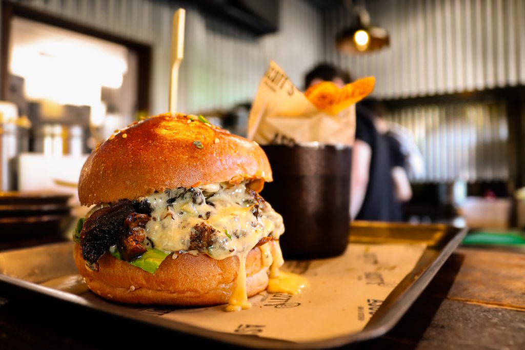 Gourmet burger with melted cheese, fresh greens, and crispy bacon served at Ascotts Restaurant.