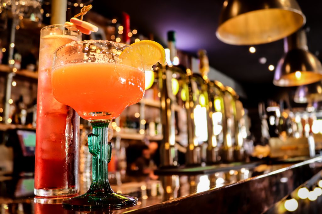 Cocktail with lemon slice at Ascotts Restaurant bar in Bromsgrove, showcasing a vibrant drink scene.