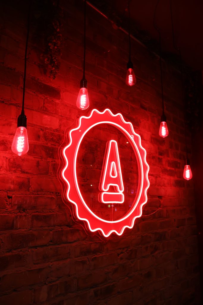 Neon sign featuring a paintbrush logo illuminated in red at Ascotts Bromsgrove sports bar. Perfect f.