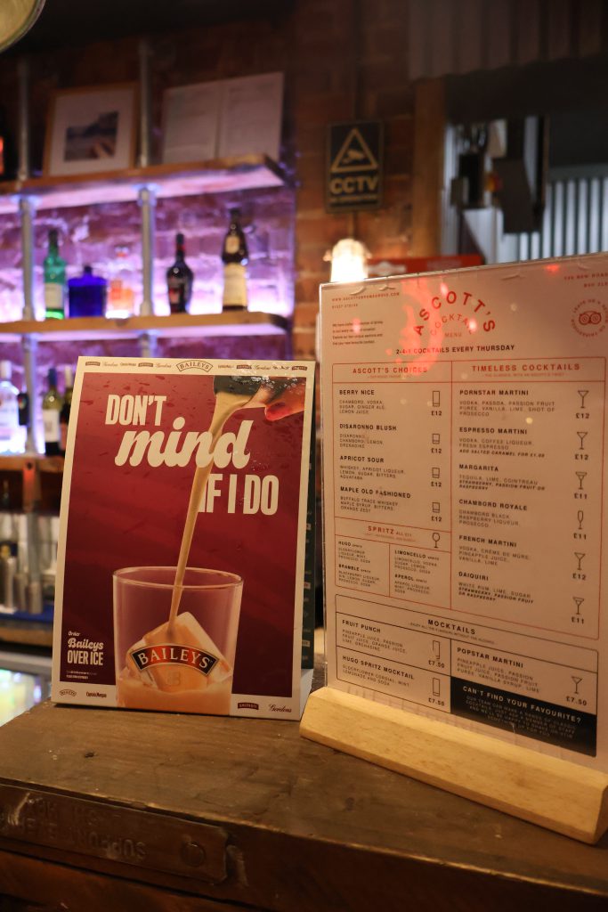 Modern bar area at Ascotts Restaurant with drinks and menu displays.